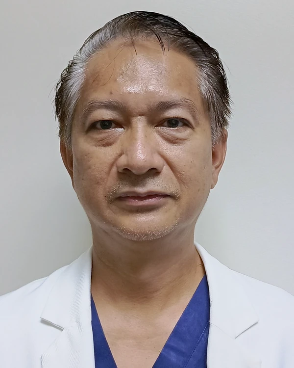 Dr. Peter Clifford Suller, MD, a Philippine urologist, in a white coat over surgical scrubs